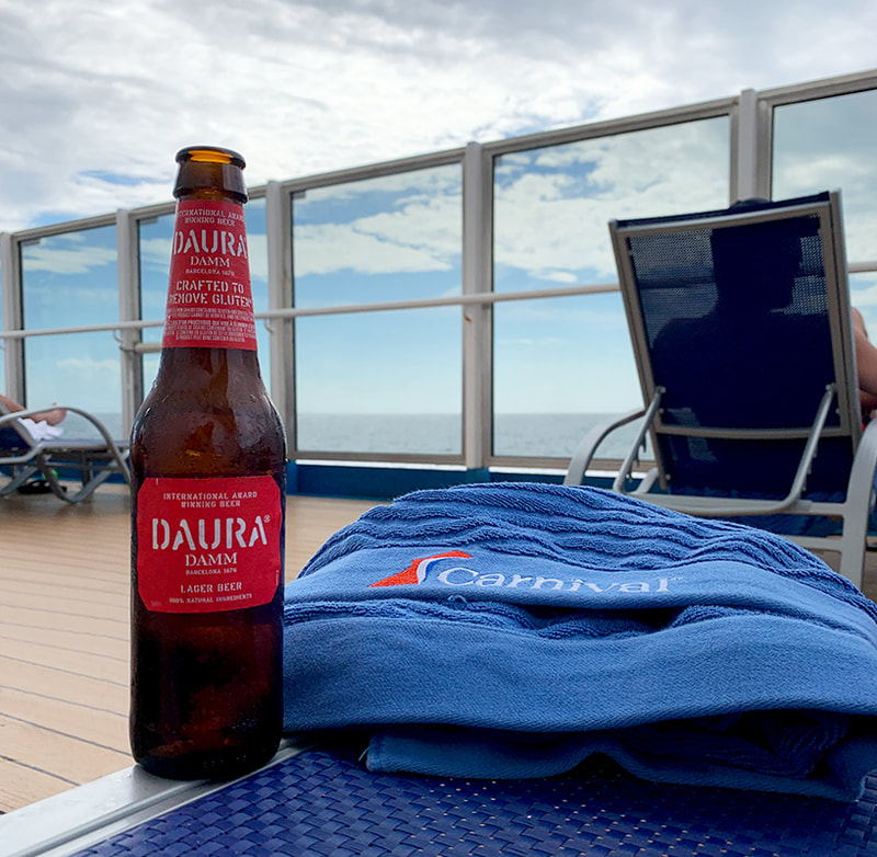 Daura Damm beer bottle and Carnival towel on ship deck